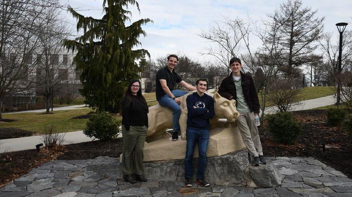 四名男学生在尼塔尼狮子雕像前摆姿势拍照